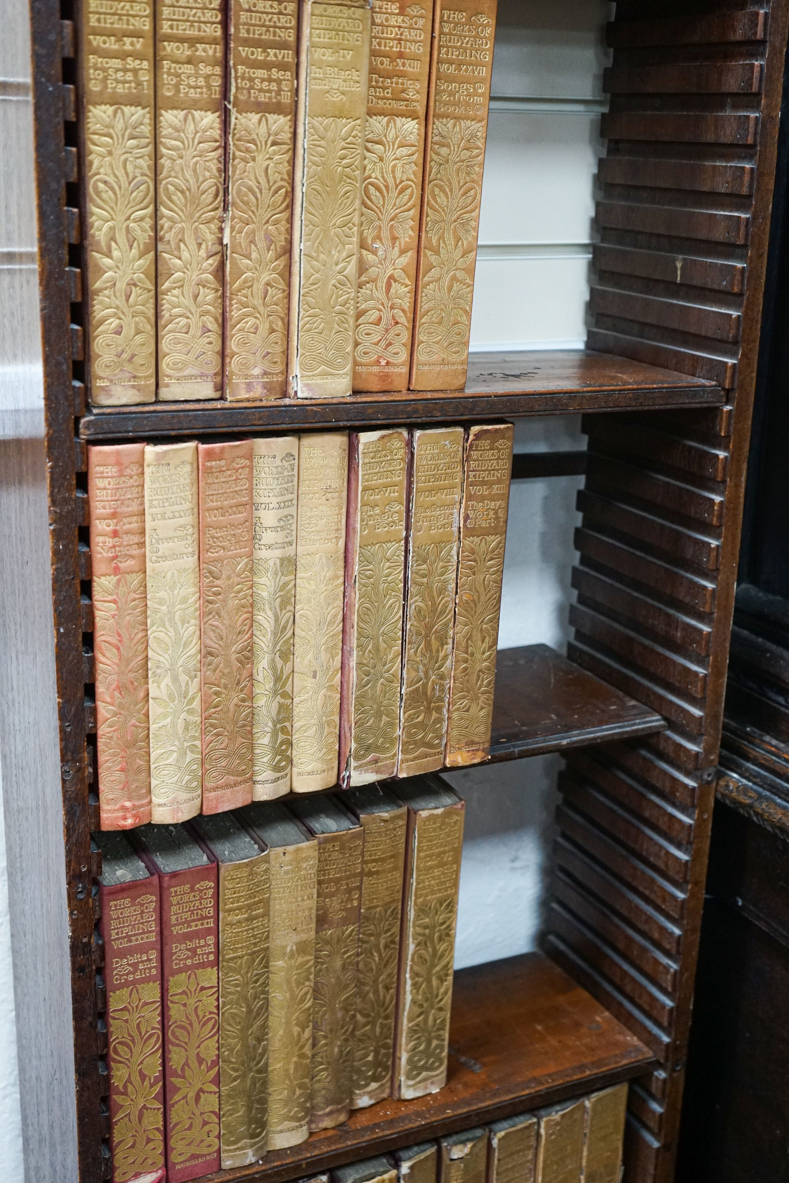 A Georgian mahogany wall-mounted narrow bookshelf, width 48cm, depth 18cm, height 147cm, containing a limited edition Works of Rudyard Kipling in 33 volumes, published 1900